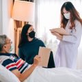 Asian doctor visit and examines a senior man at home ,The doctor checking up and consulting for retirement health partient,hospital services ,and wearing a mask to protect covid-19.