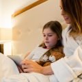 Mother and daughter using digital tablet in bedroom at home